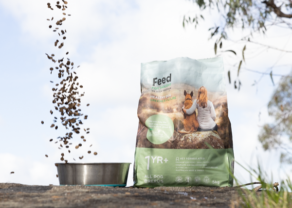 Feed For Thought 5kg dog food bag outdoors with kibble pouring into a metal bowl, featuring a woman and dog on the packaging.