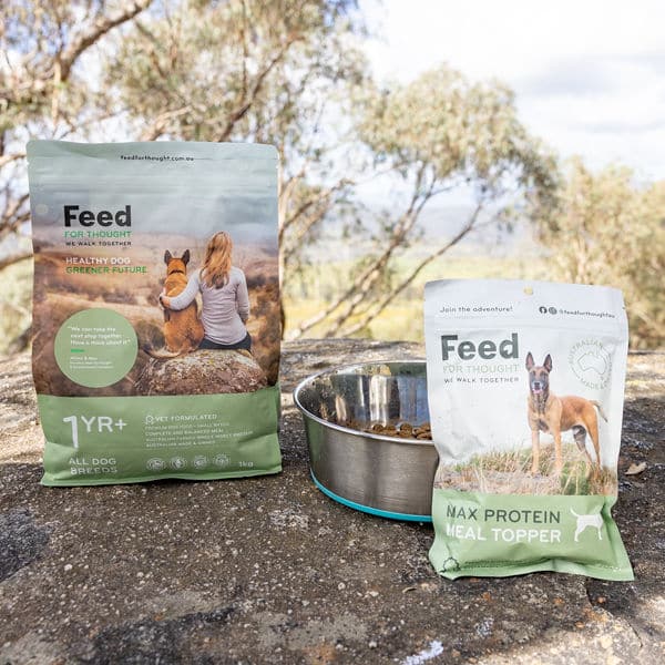 meal topper packet with bowl and bag of 1kg dry food on a rock