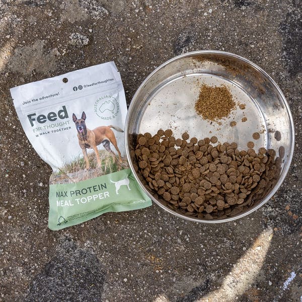 dry dog food and meal topper in bowl with packet of topper on rock